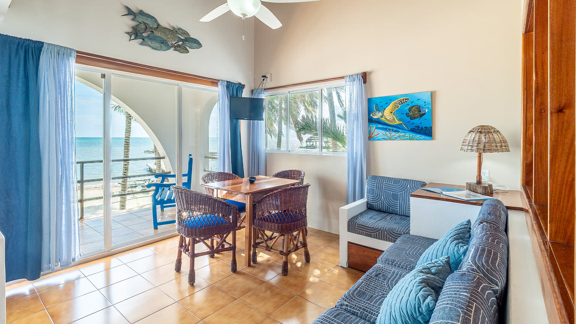 Cozy beachfront living area with a dining table, woven chairs, and a view of the ocean.